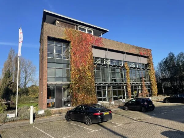 Kantoorgebouw aan de Jan Leentvaarlaan met klimplanten op de gevel en geparkeerde auto's op de voorgrond.